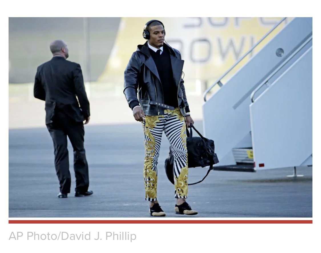 Cam Newton walking on tarmac carrying bag